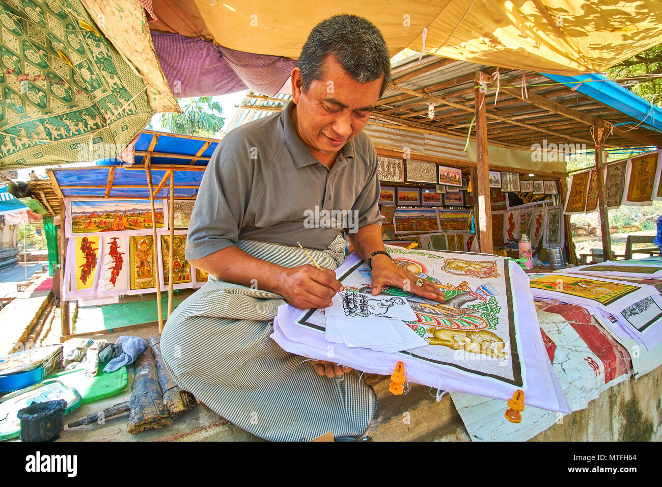 BAGAN, MYANMAR - FEBRUARY 24, 2018: The smiling artist painting an elephant on the paper in traditional burmese style, on February 24 in Bagan Stock Photo