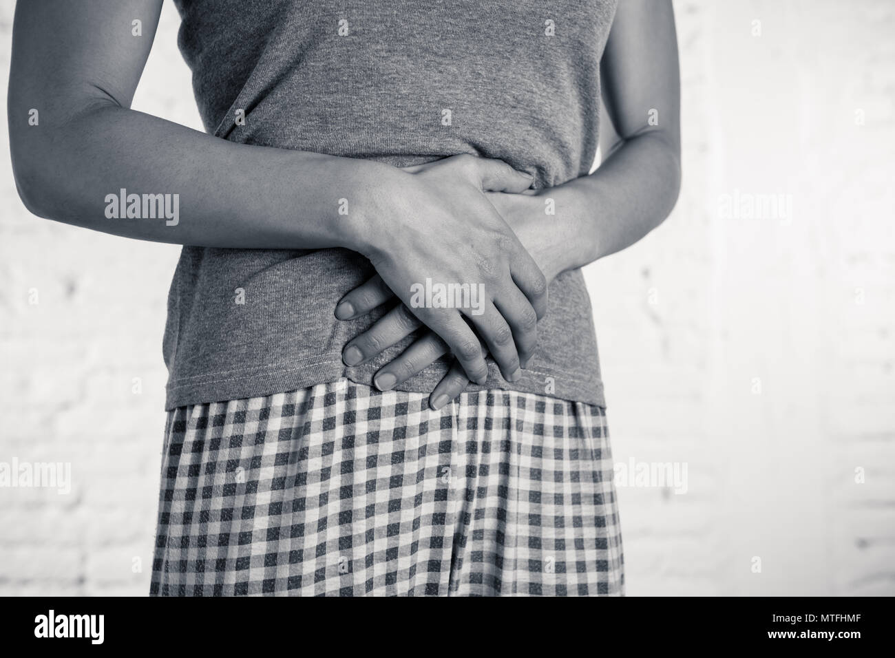 Close up of a young woman having painful stomachache holding hands on her belly. Body pain