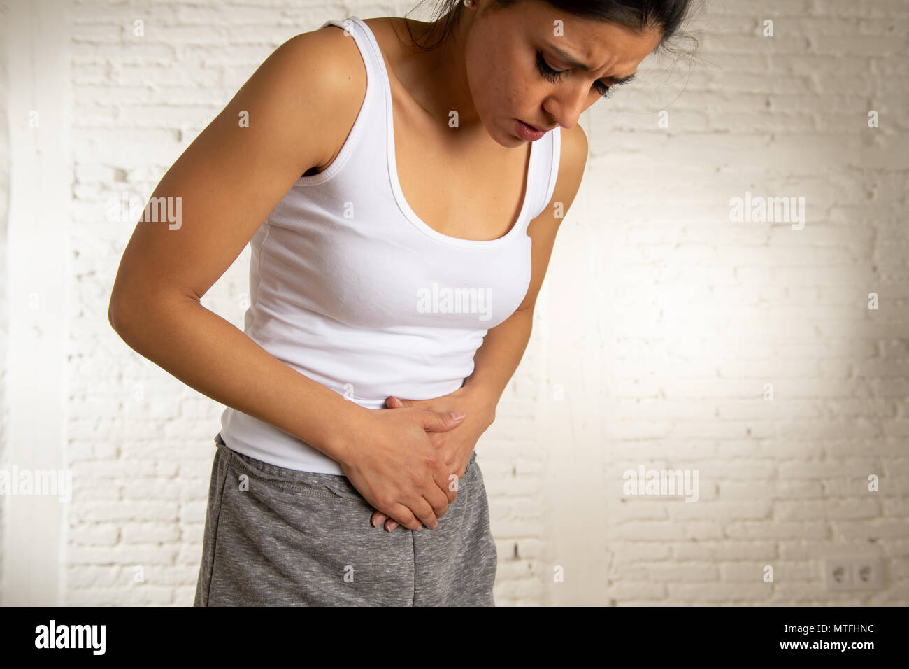 Close up of a young woman having painful stomachache holding hands on her belly. Body pain