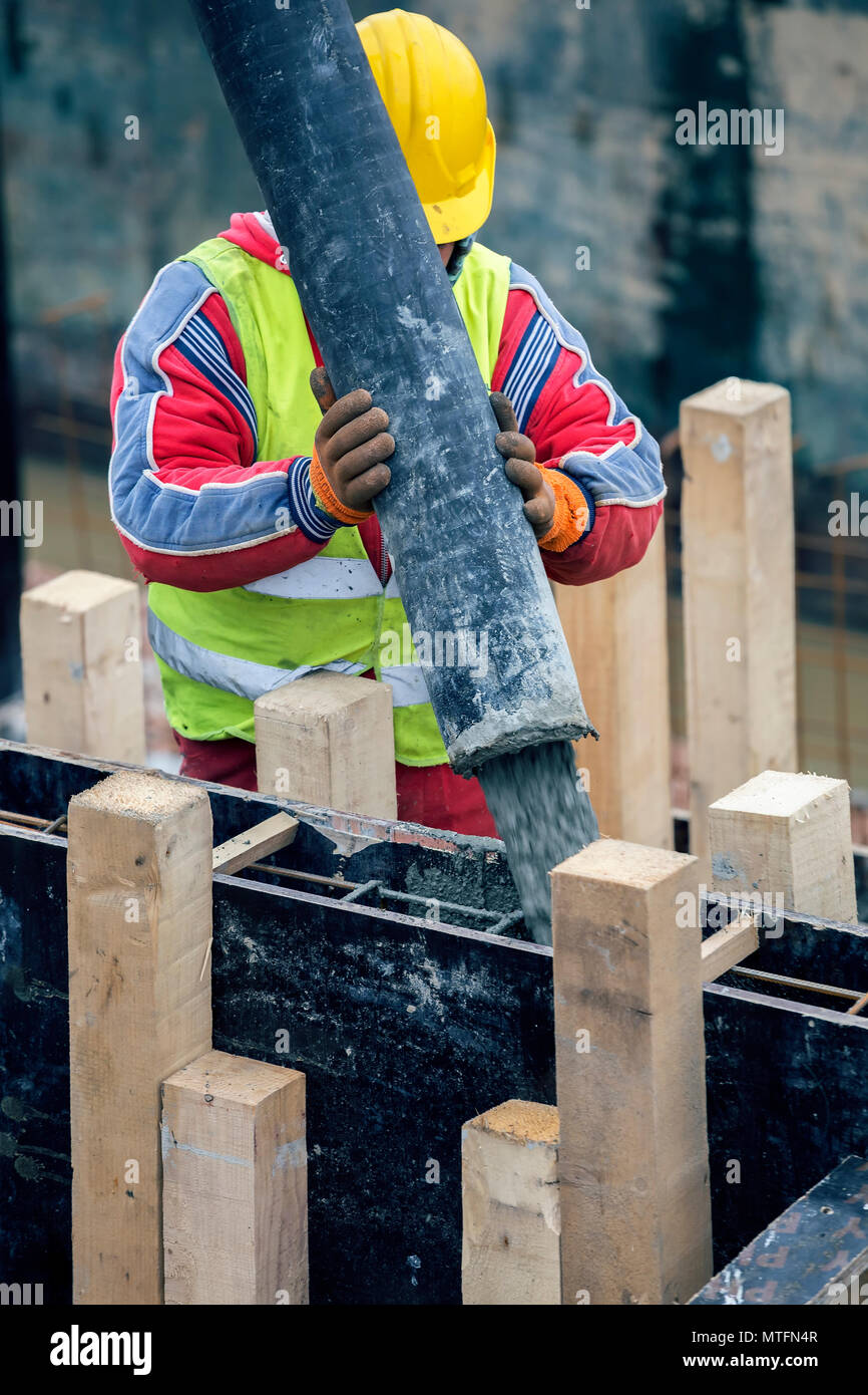 Pouring concrete footing from cement mixer on concreting formwork. Pour concrete footings
