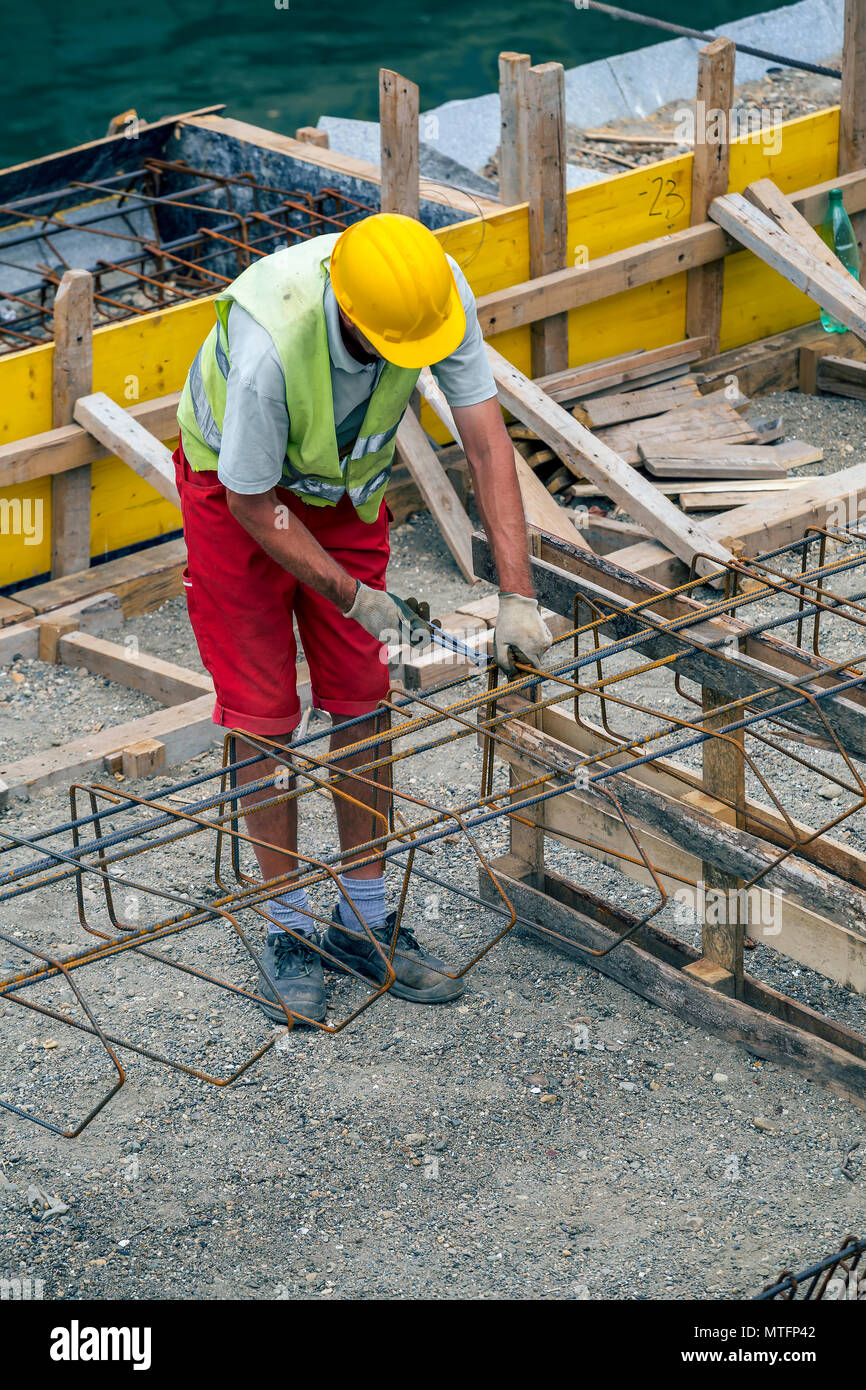 Worker at the construction site making reinforcement metal framework ...