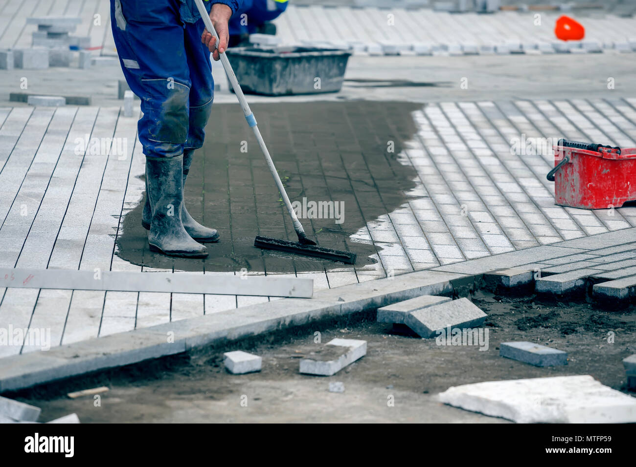Worker filling the paver joints, full paver joints will help prevent the paving stones from
