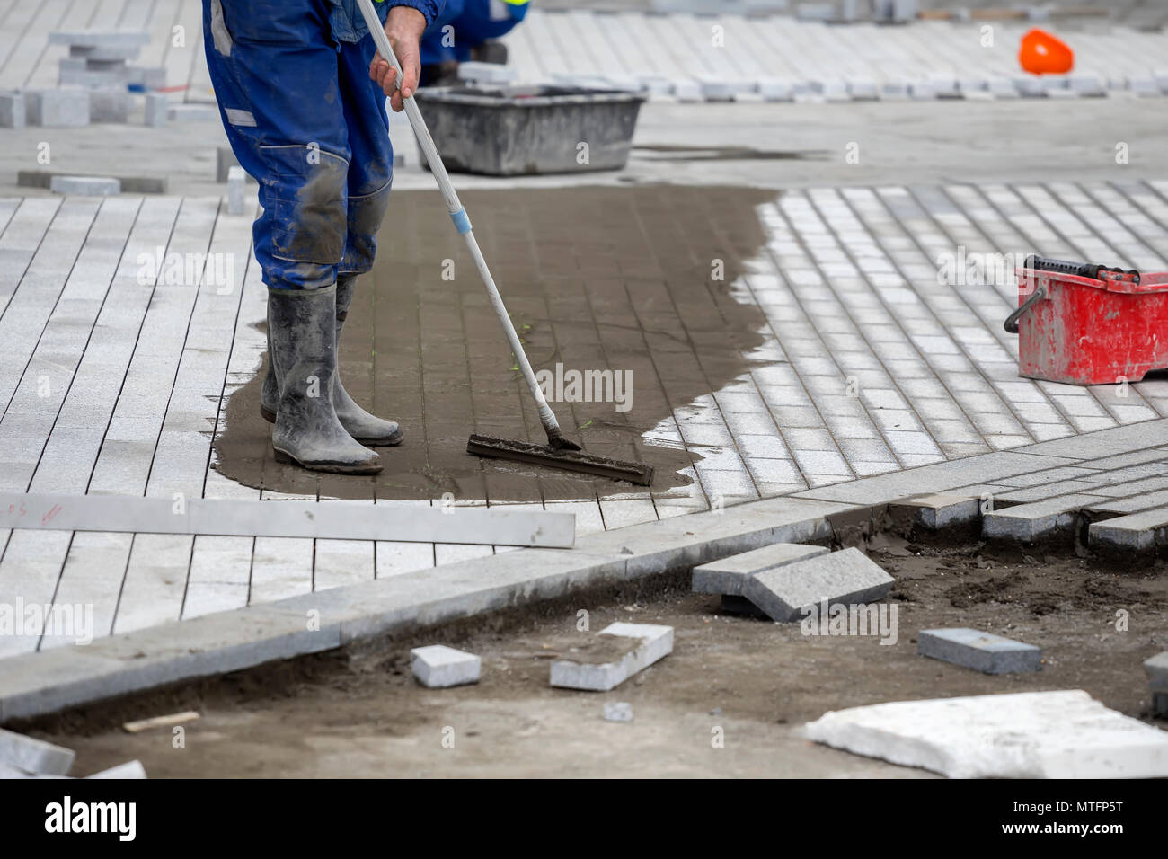 Worker filling the paver joints, full paver joints will help prevent