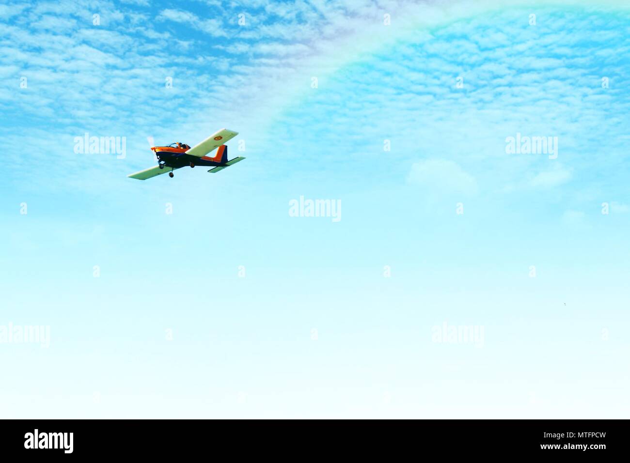 Airplane flying between clouds with a rainbow Stock Photo - Alamy