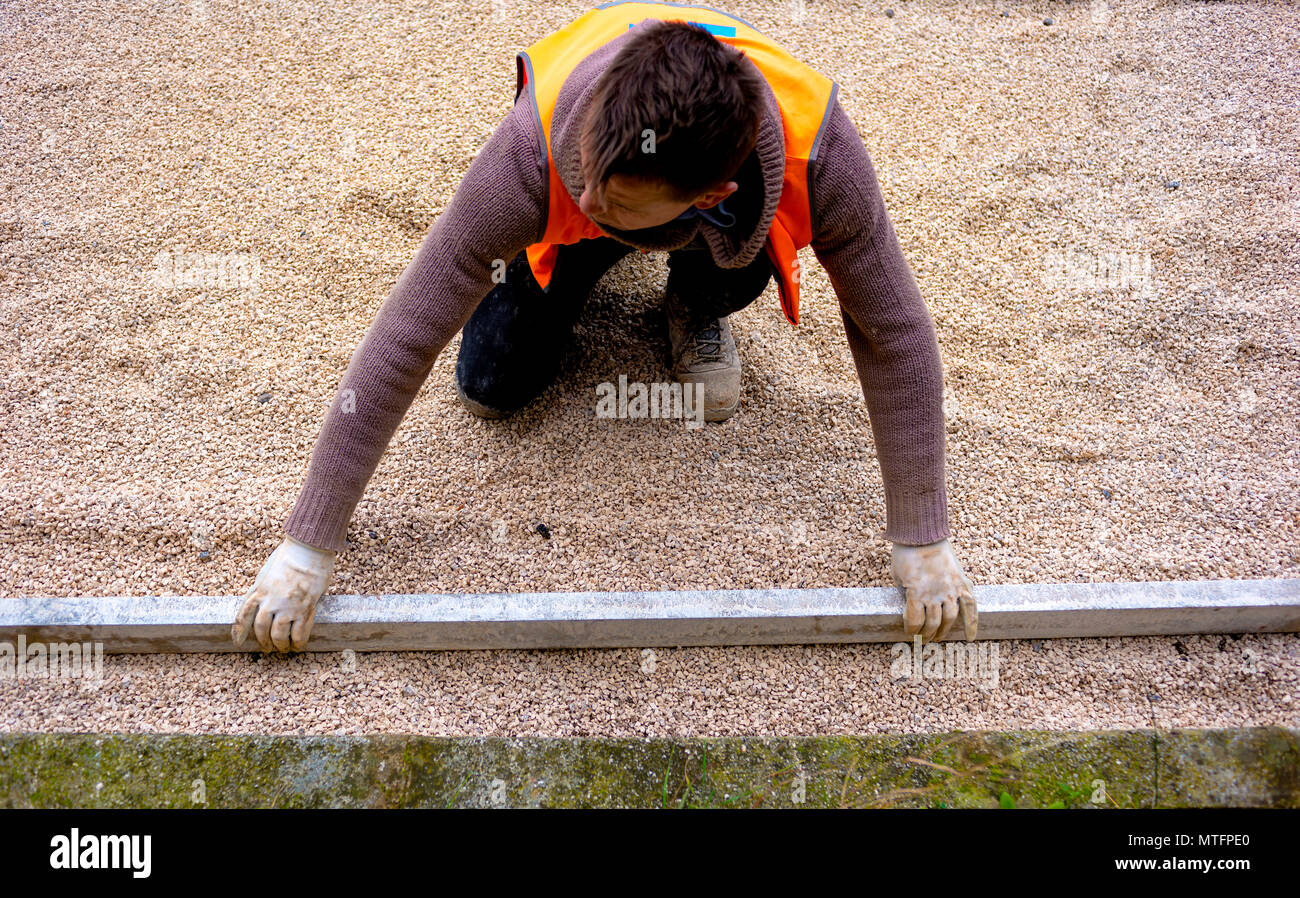 Construction worker laying interlocking paving concrete onto sheet