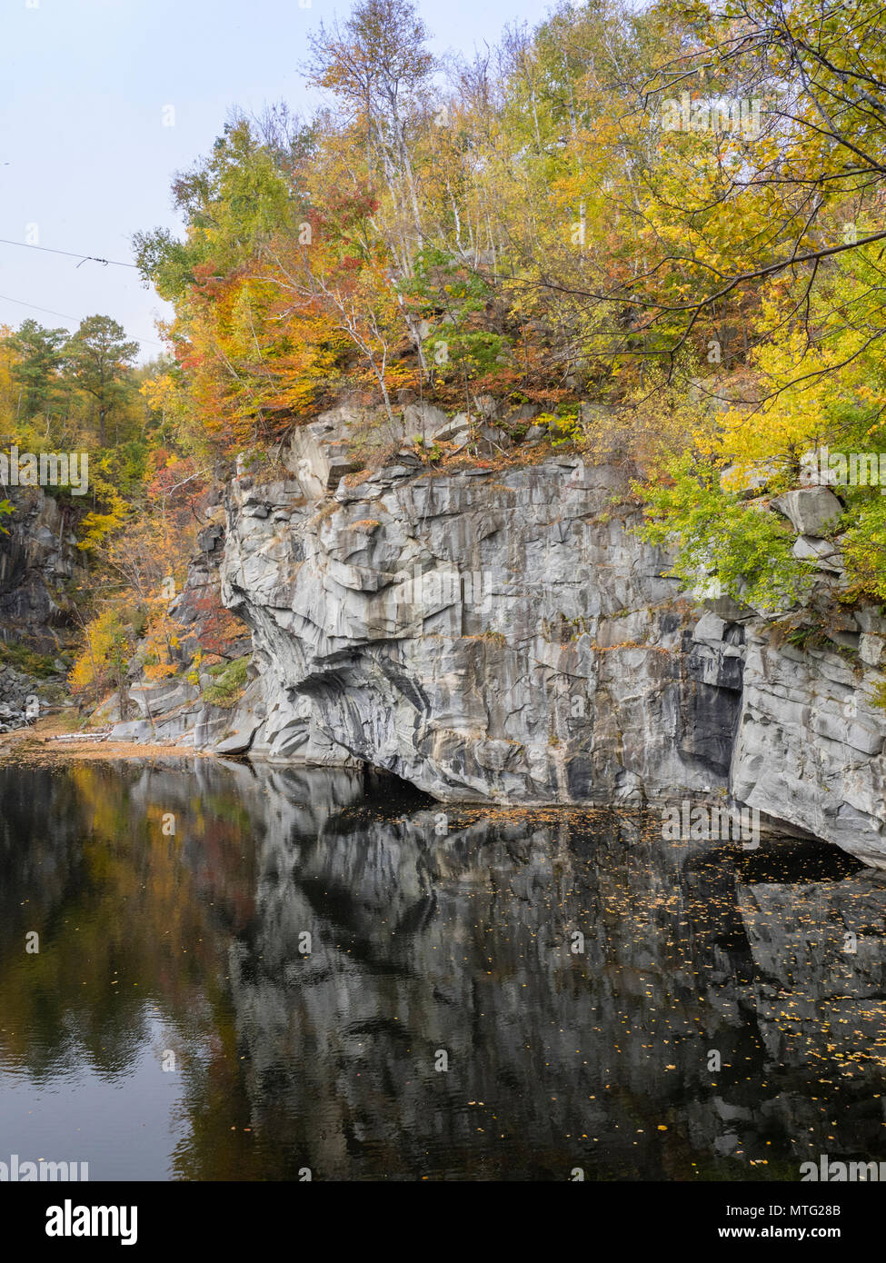 Reflections of trees and granite walls in the waters of the quarry at