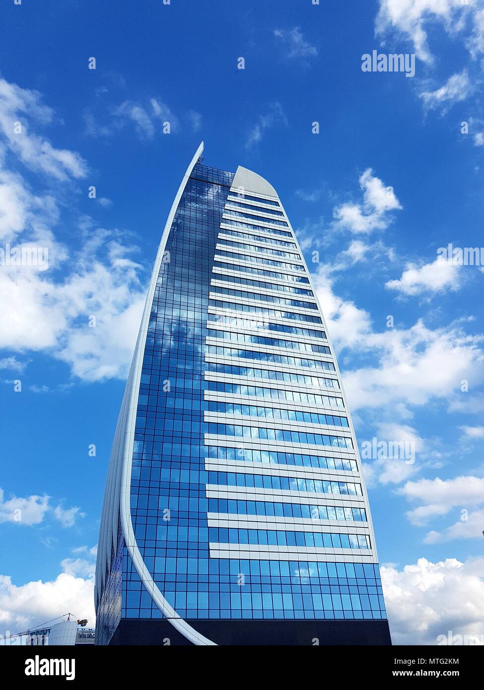 Tall office building with windows reflecting the sky with white clouds Stock Photo
