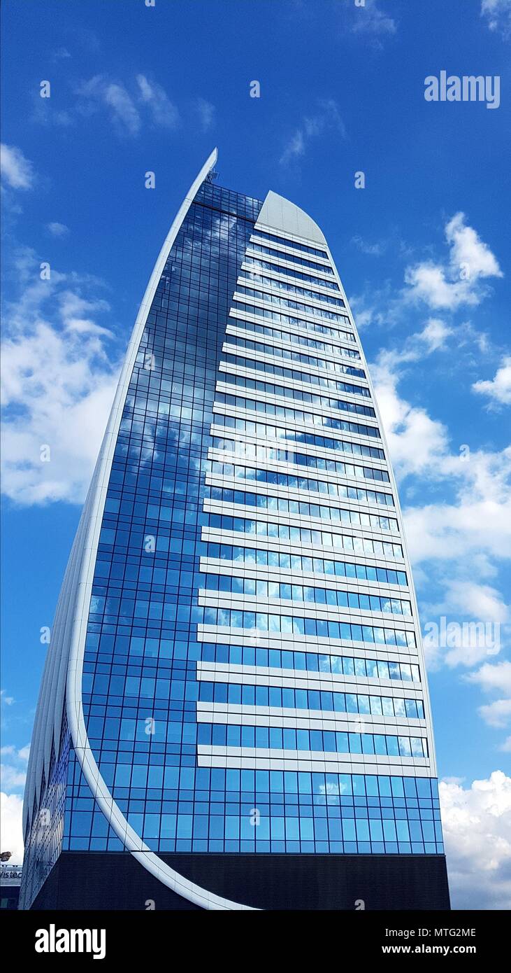 Tall office building with windows reflecting the sky with white clouds Stock Photo