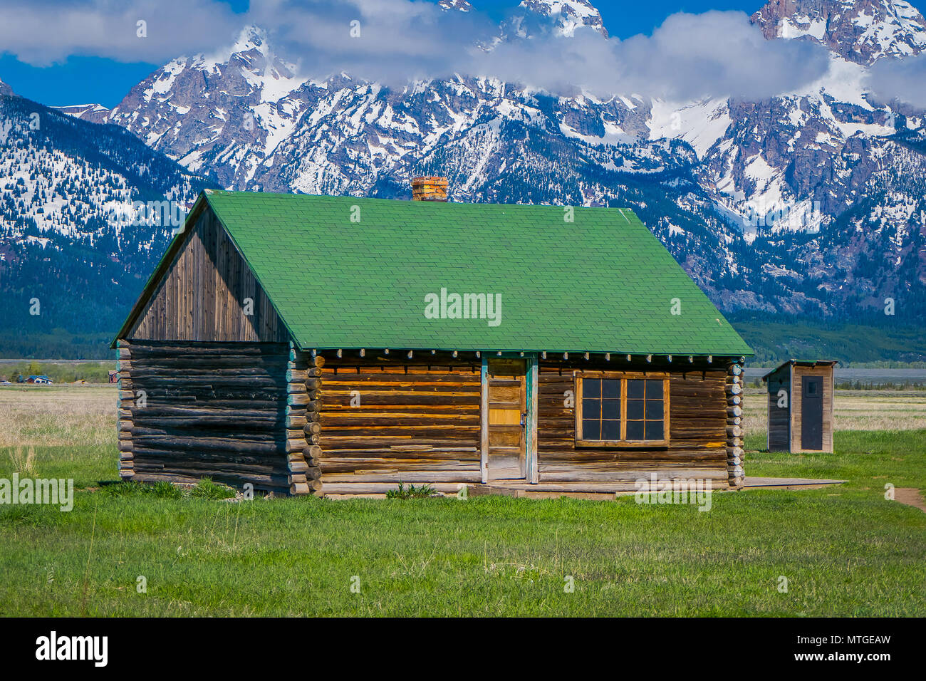 Outdoor View Of Wooden Cabin With Green Rooftop On A Golden Grass