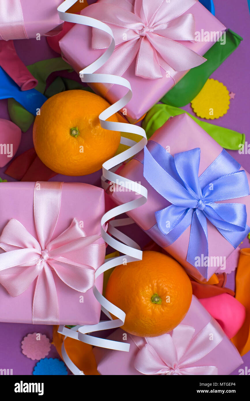 Decorative composition five boxes with gifts Satin ribbon Bow Oranges Confetti Serpentine birthday party. The view from the top Stock Photo