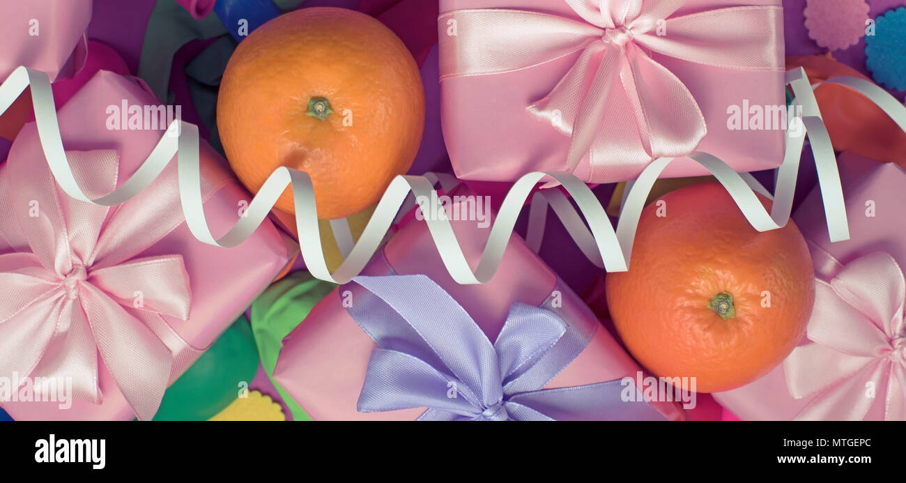 Banner Decorative composition five boxes with gifts Satin ribbon Bow Oranges Confetti Serpentine birthday party. The view from the top Stock Photo