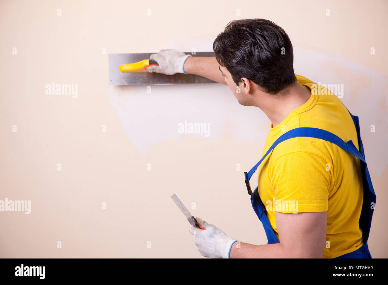 Young contractor employee applying plaster on wall Stock Photo