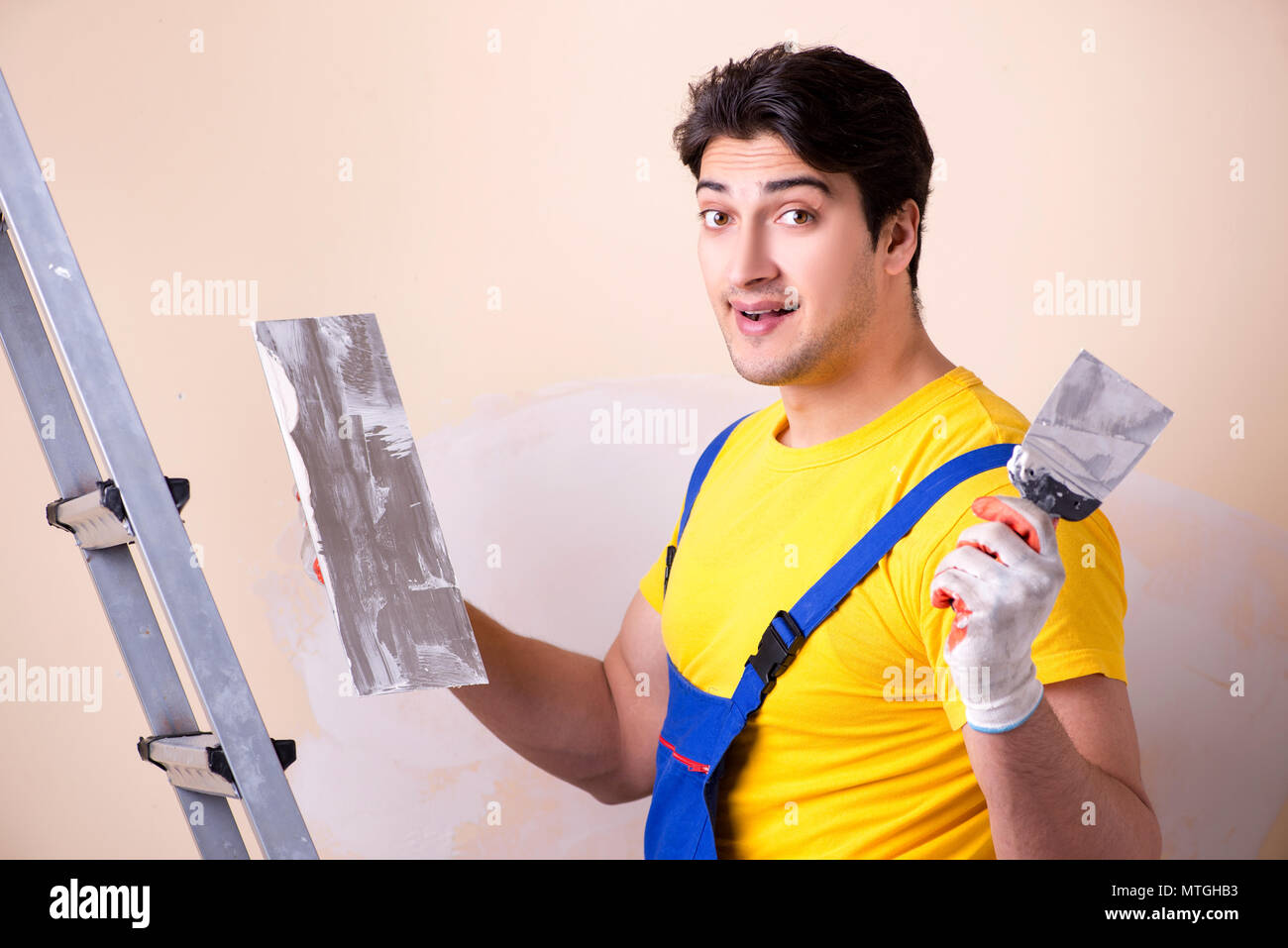 Young contractor employee applying plaster on wall Stock Photo