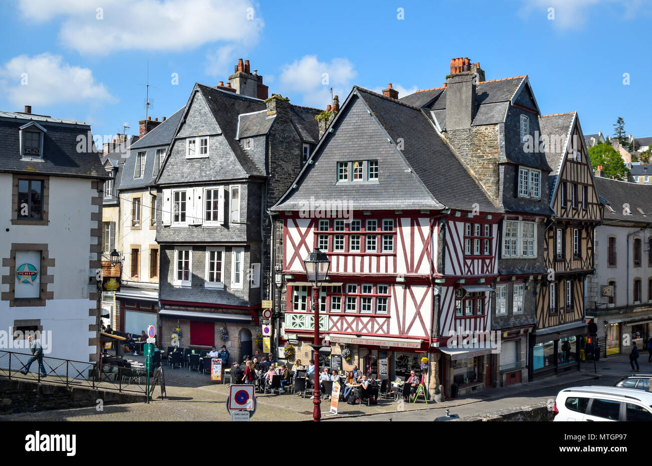 Within a half-timbered building on a busy corner, a lively cafe full of people in Morlaix, Brittany, France. Stock Photo