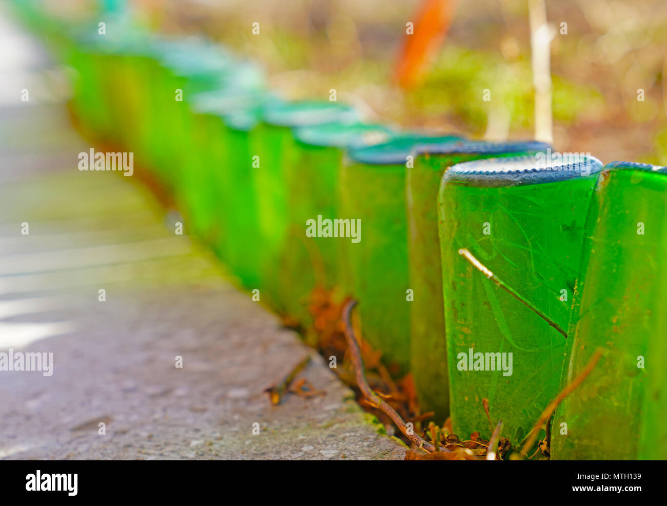 The border of the garden is made of non-returnable green glass bottles Stock Photo