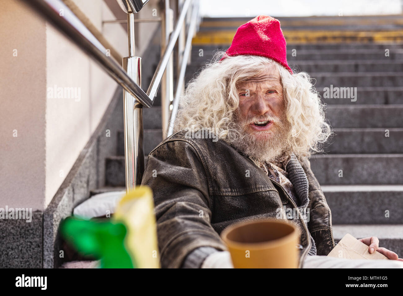Cheerless homeless man sitting on the street Stock Photo