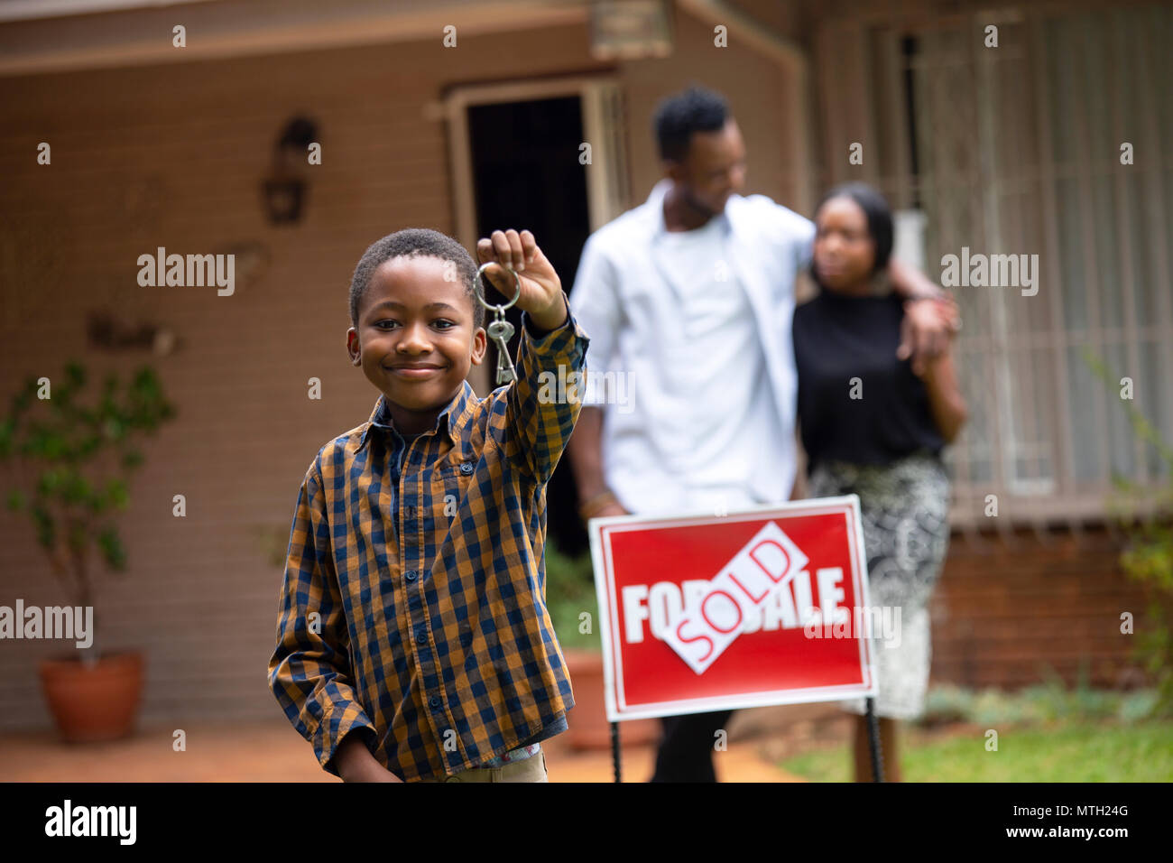 Boy holding keys in front of new house Stock Photo