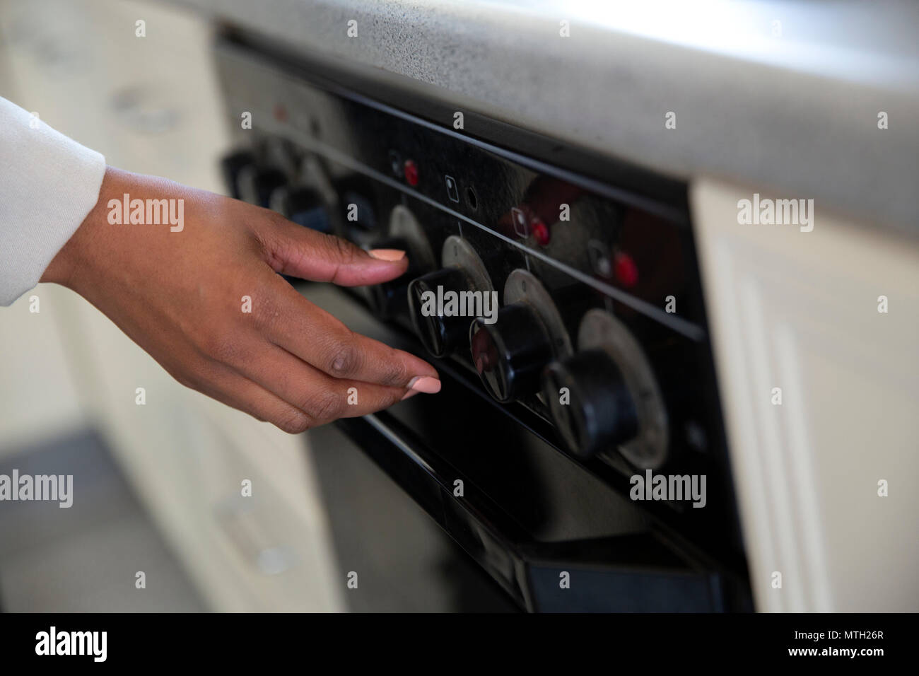 Woman turning on stove Stock Photo