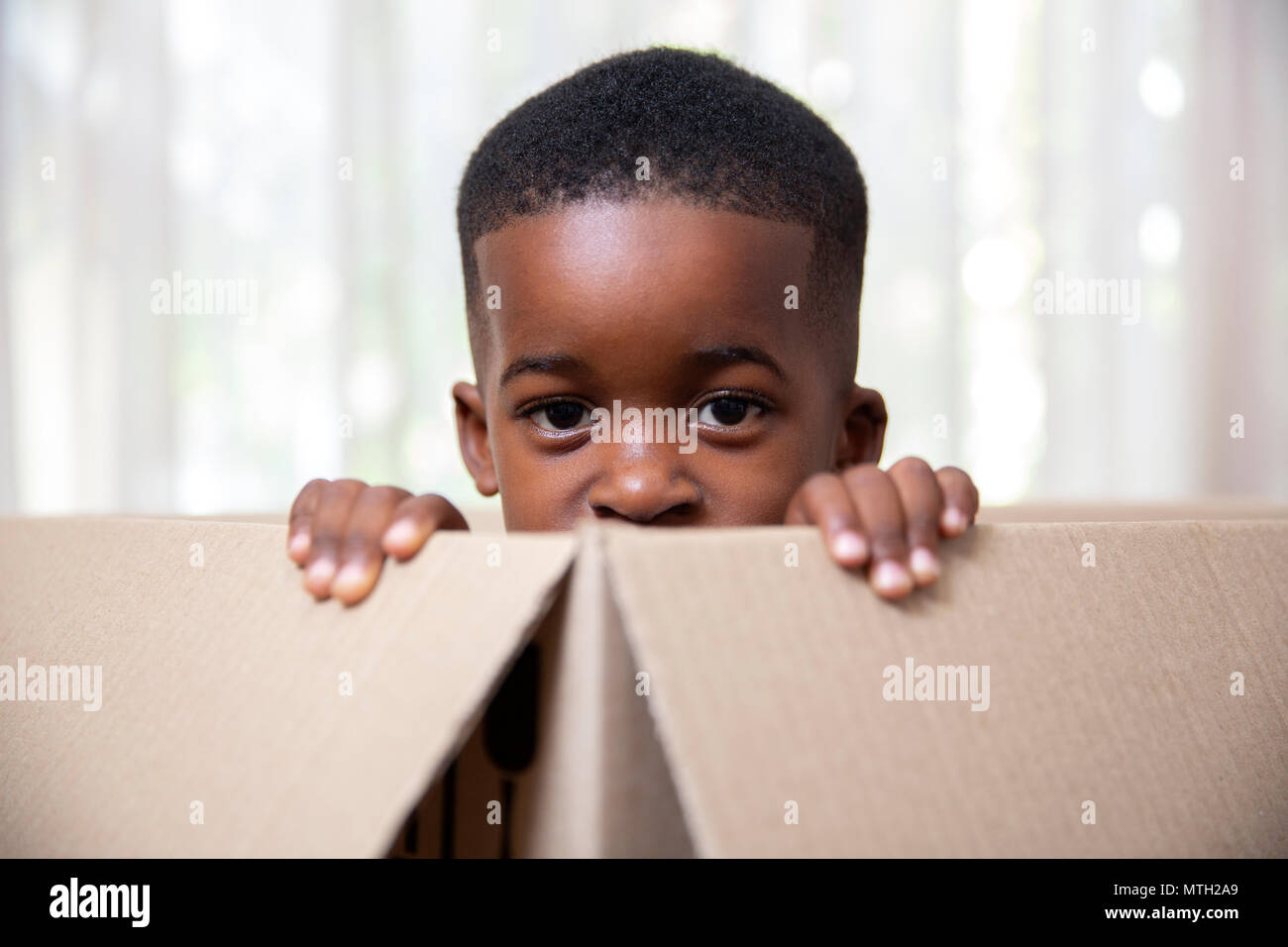 Boy peeping out of cardboard box Stock Photo