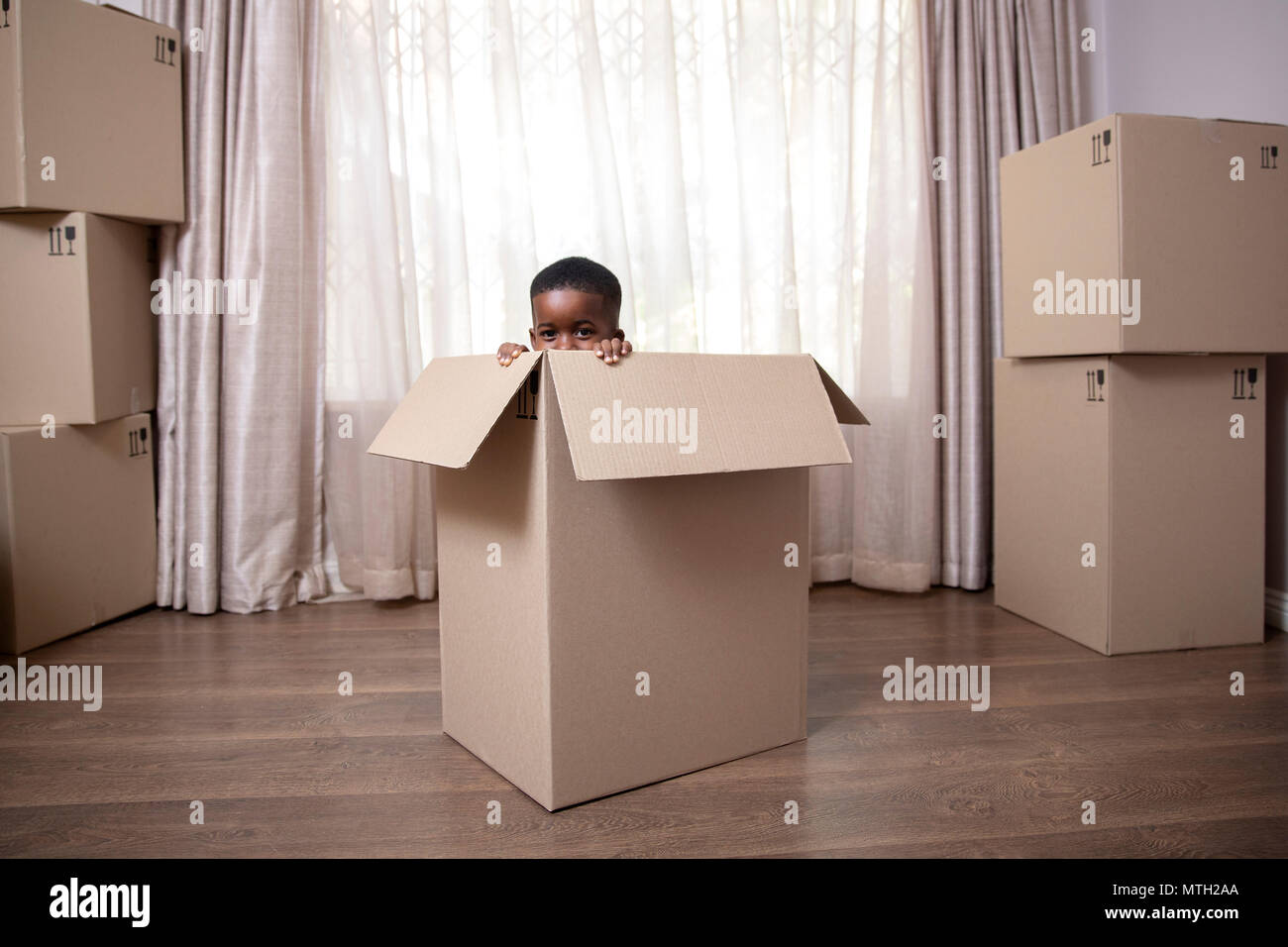 Boy peeping out of cardboard box Stock Photo