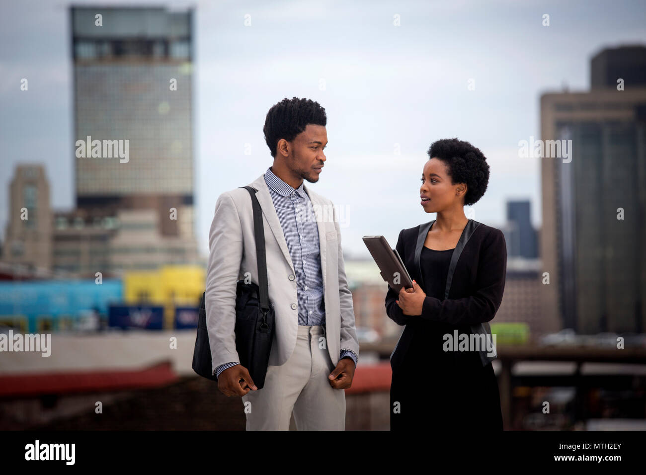 Business man and woman talking on rooftop Stock Photo