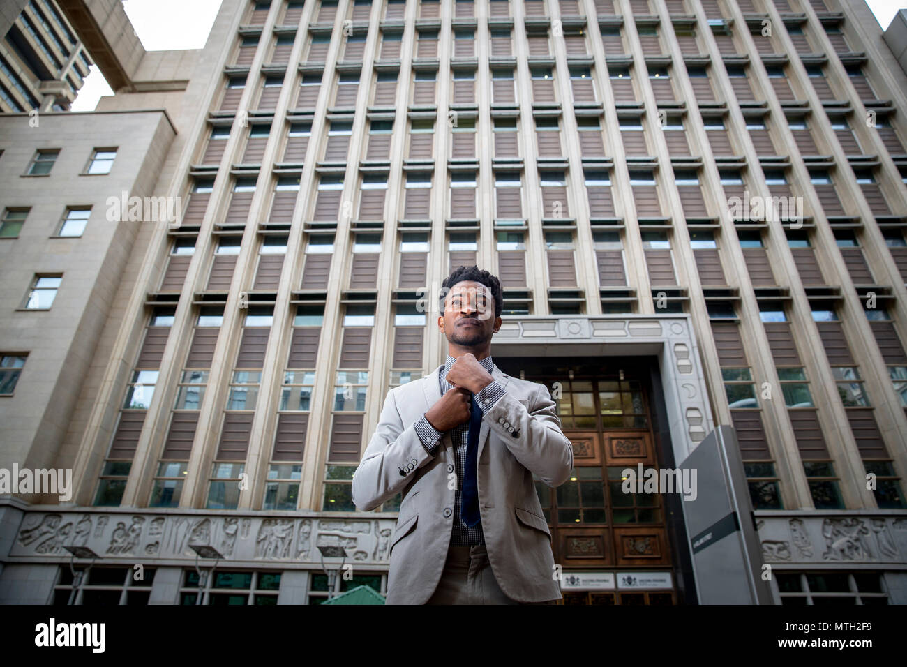 Business man fixing tie in front of office block Stock Photo