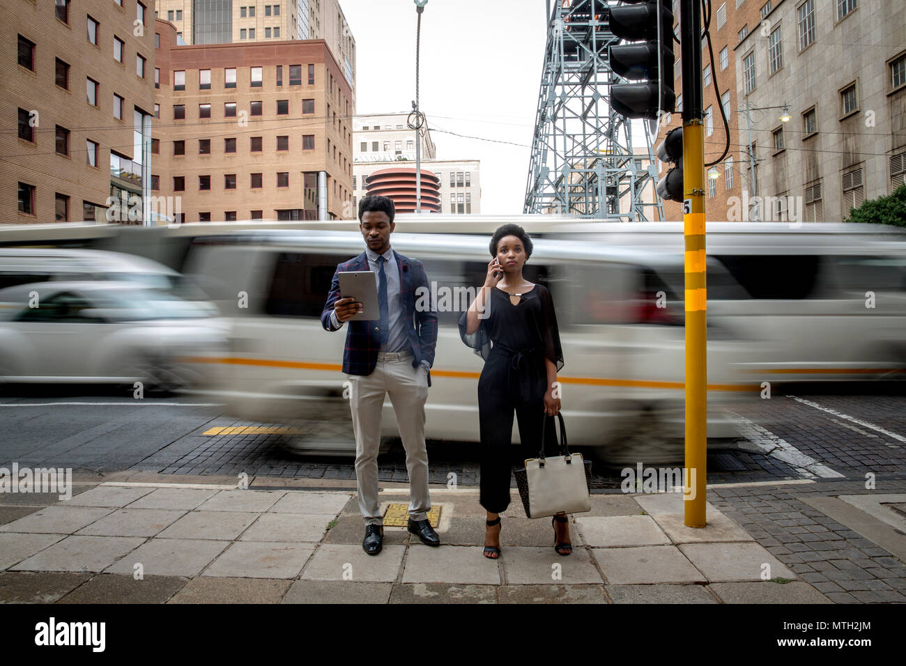 Business man and woman waiting at traffic light Stock Photo