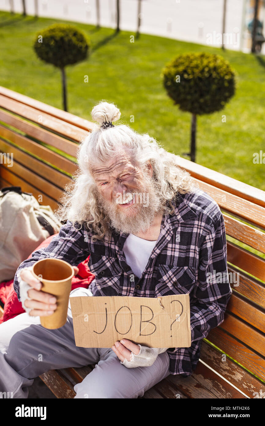 Cheerless homeless man holding a plastic cup Stock Photo