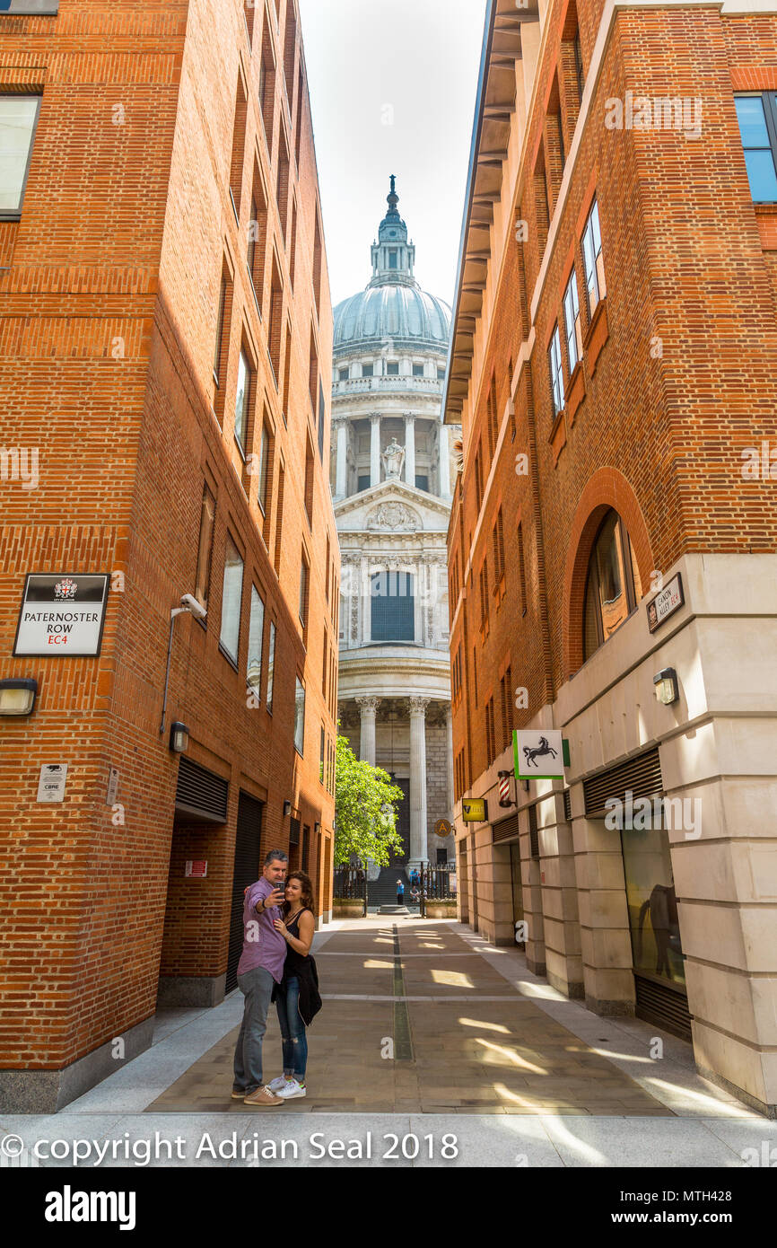 A couple taking a selfie photograph from Paternoster Row with St. Paul's Cathedral in the background London England UK Stock Photo