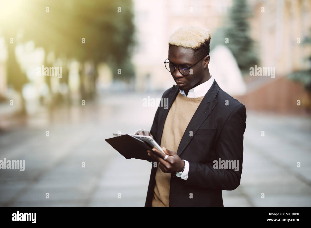 Businessman using his tablet computer in the city street Stock Photo