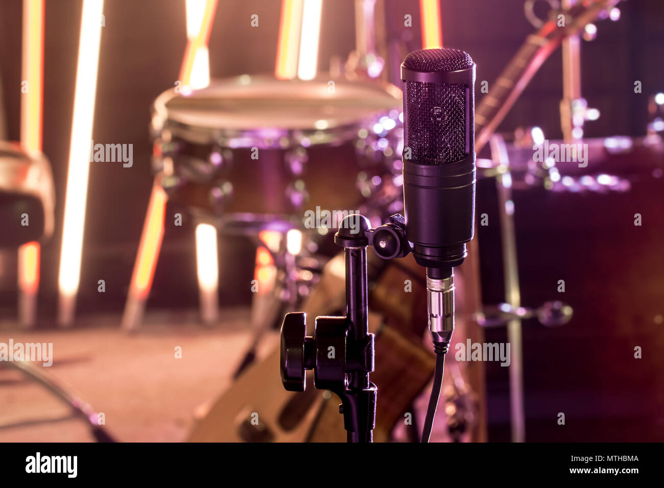 The microphone in a recording Studio or a concert hall close up of drum kit and an acoustic guitar in the background. Beautiful blurred background of  Stock Photo