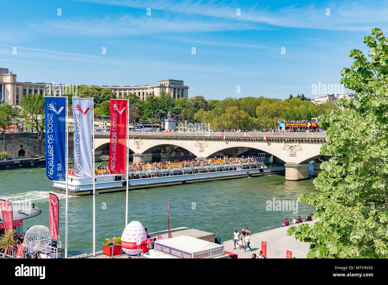One of the many tour boats working the Seine River in Paris goesunder a busy bridge in Paris. Stock Photo