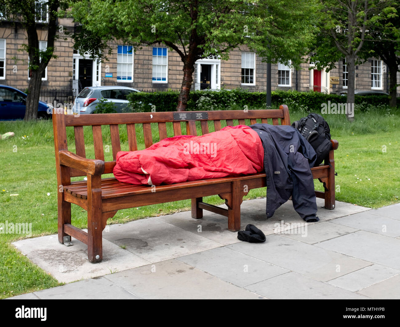A rough sleeper on a park bench in the New Town, Edinburgh, Scotland, United Kingdom Stock Photo
