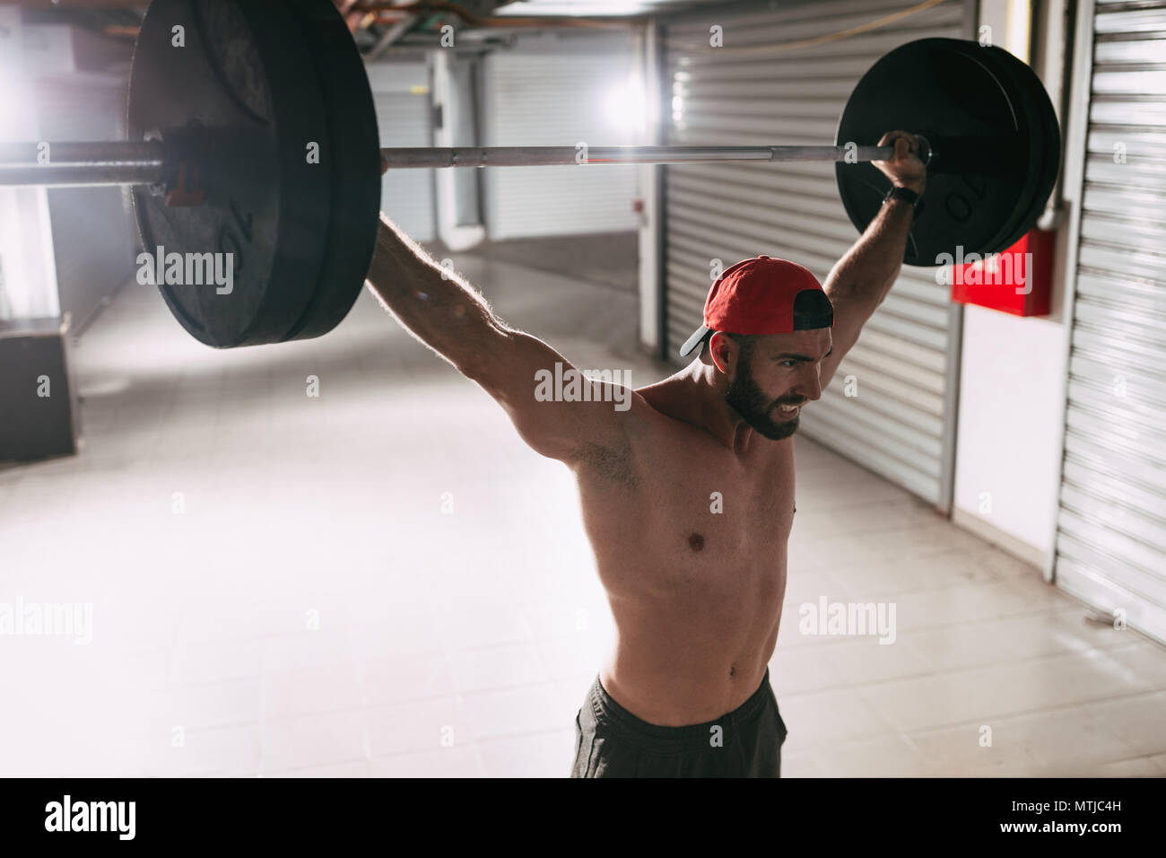 Man Snatche Exercise Young muscular man doing snatch exercise with barbell on hard training ...