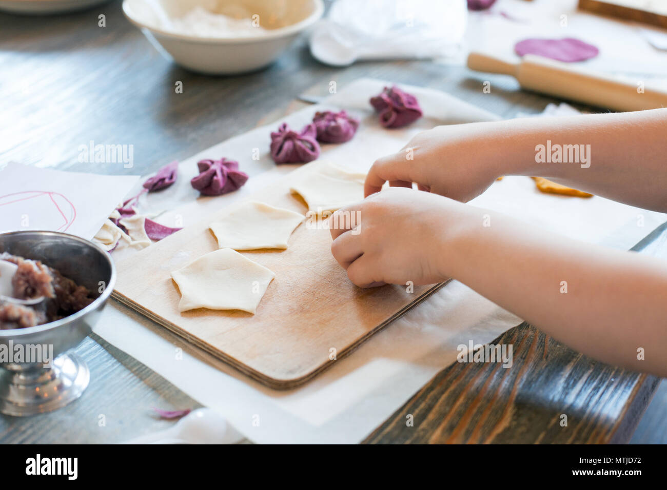 cooking class, culinary. food and people concept/ molding of pelmeni or meat dumplings, child hands in process Stock Photo