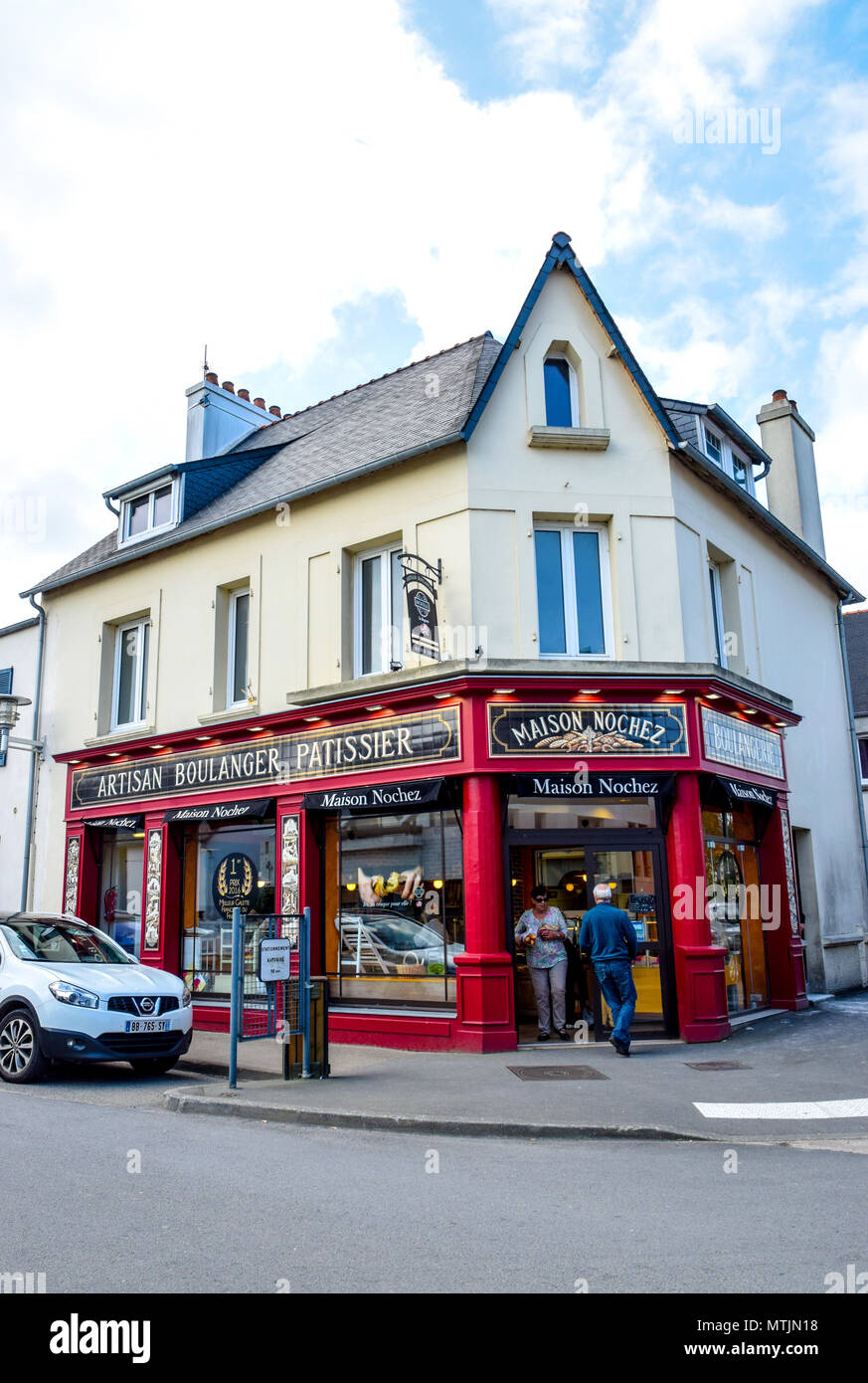 The boulanger and patissier in Carantec, Brittany, France sells their bread and pastries from a bright-coloured corner shop. Stock Photo