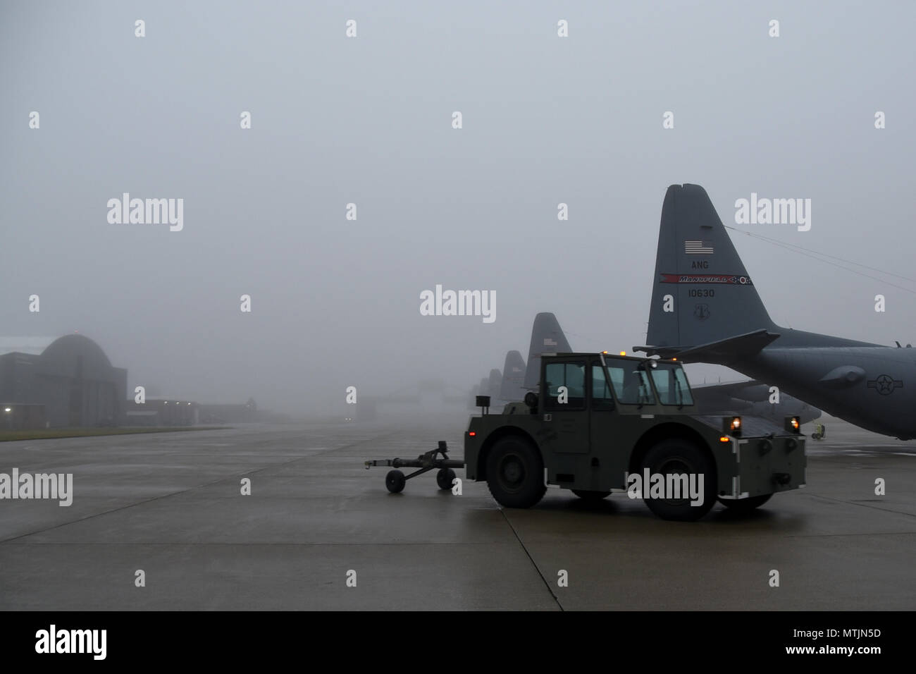 Master Sgt. Kristopher Wolf drives a tow motor through a blanket of fog Jan. 3, 2017, on the flightline at the 179th Airlift Wing, Mansfield, Ohio. The 179th Airlift Wing is always on a mission to be the first choice to respond to community, state and federal missions with a trusted team of highly qualified Airmen. (U.S. Air National Guard photo by Airman Megan Shepherd/Released) Stock Photo