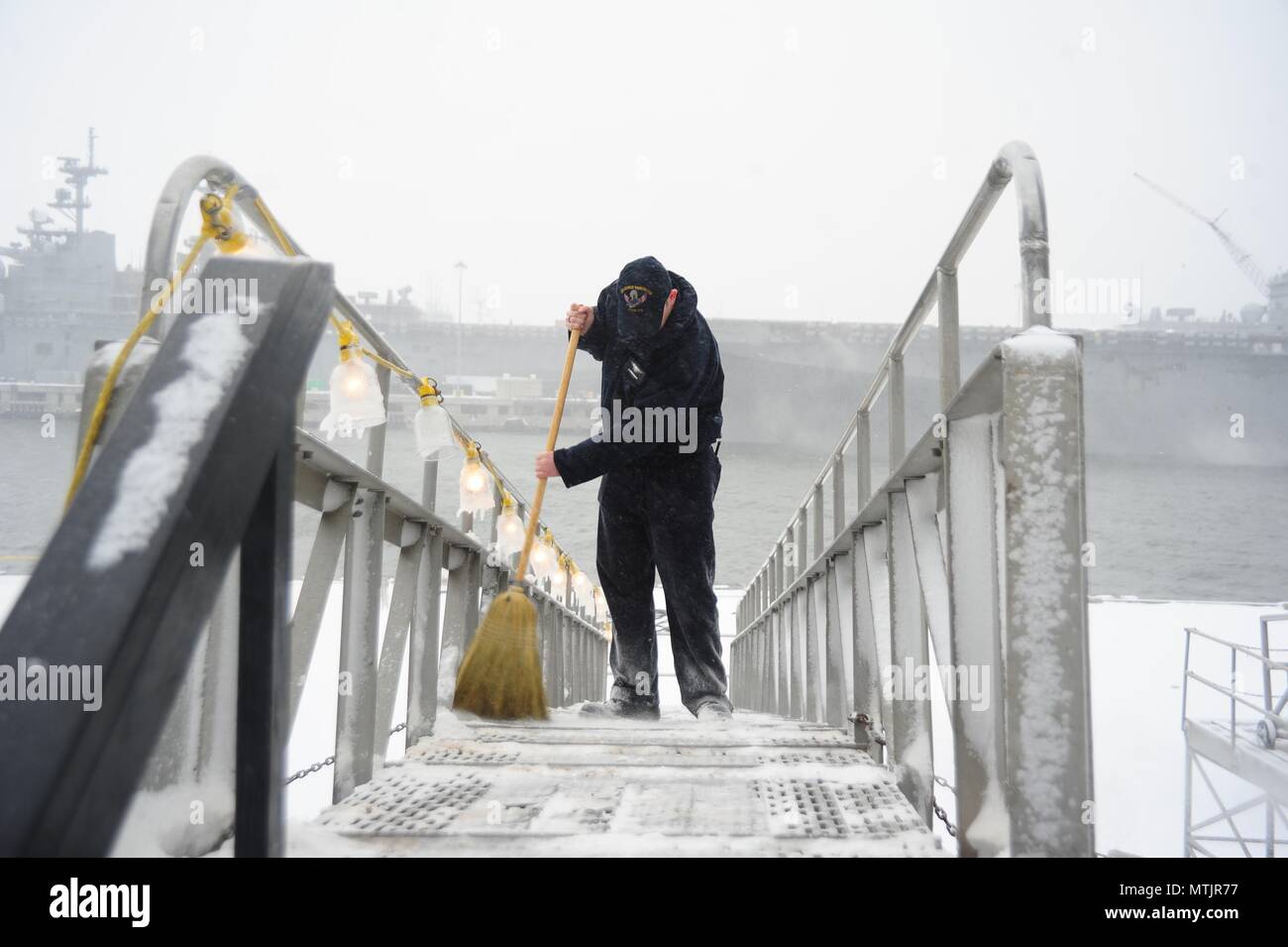 Aviation Boatswain's Mate (Launching and Recovery) 1st Class Cameron Owens sweeps snow off the