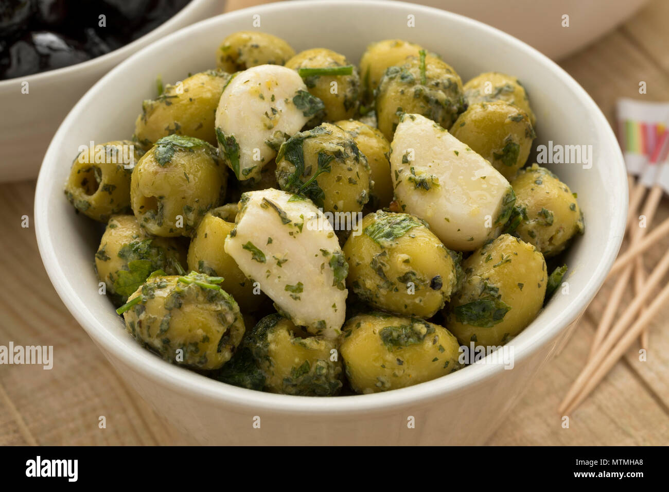 Bowl with green olives, garlic and cilantro as a snack close up Stock Photo