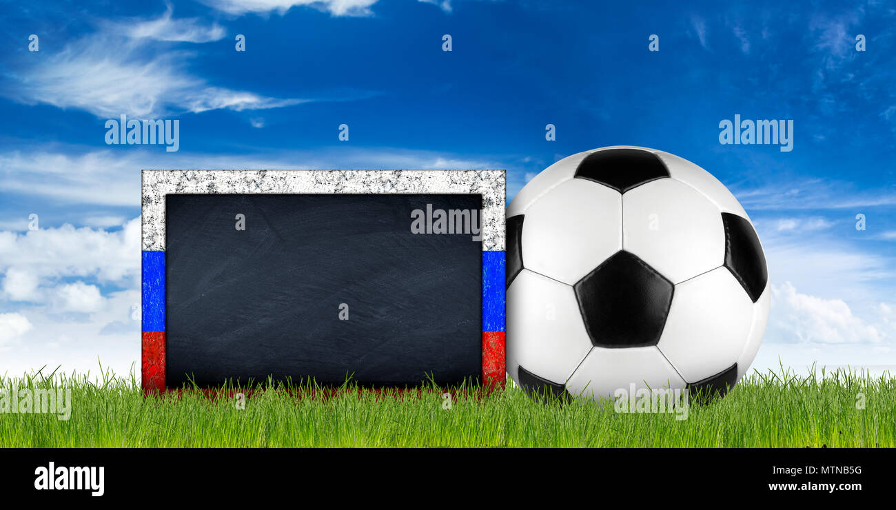 empty russian flag frame blackboard with copy space retro black white leather soccer ball on green grass field in front of blue sky background Stock Photo