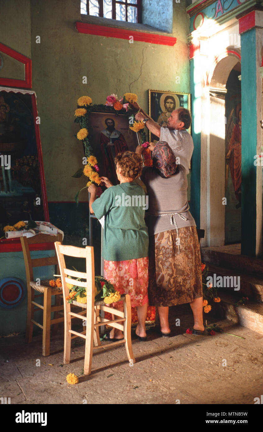 People decorate the icon in a rural church on the eve of the feast of St. Nikitas, Sellas, Peloponnese, Greece. Stock Photo