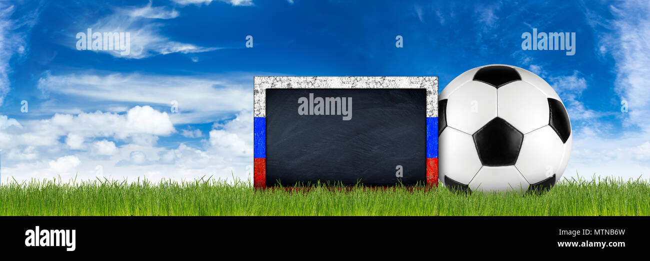 empty russian flag frame blackboard with copy space retro black white leather soccer ball on green grass field in front of blue sky wide panorama bann Stock Photo