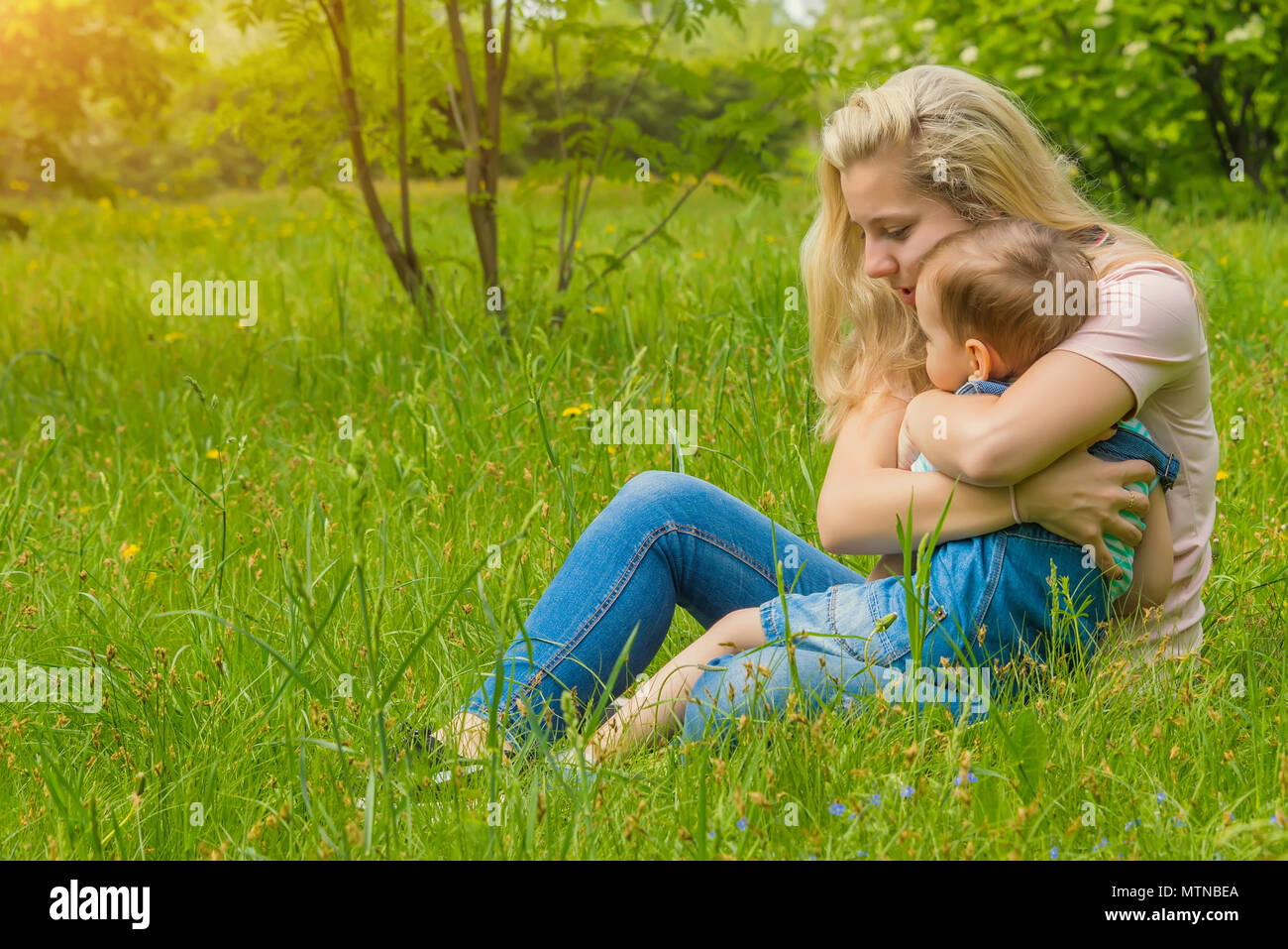 mother and child in nature in the Park, resting on the green grass in ...