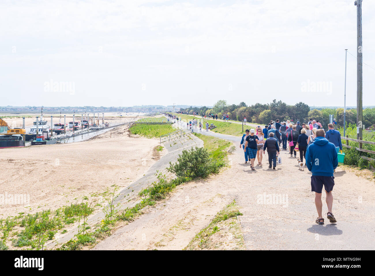 Wells-next-the-Sea, Norfolk, UK. 27th May 2018. People walking along the footpath leading to the beach of Wells on a sunny warm day during the Bank Ho Stock Photo