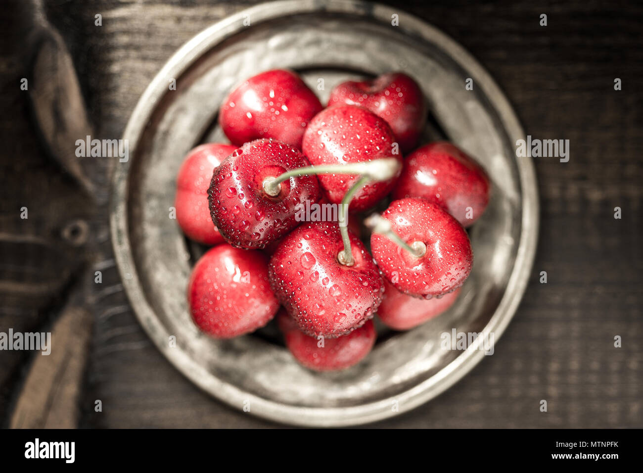Red Cherries with Water Drops in Rustic Saucer Stock Photo