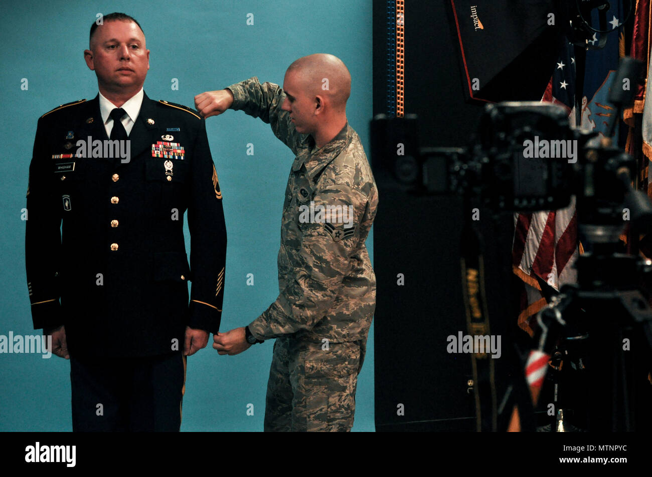 U.S. Air Force Airman 1st Class Randall Moose, 17th Training Wing Public  Affairs photojournalist, adjusts the uniform of U.S. Army Sgt. 1st Class  Corey Whigham, 344th military intelligence battalion, before taking an