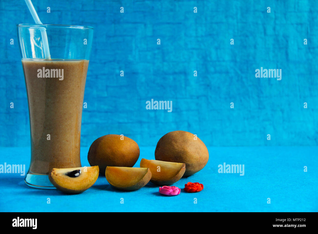 Chikoo or sapota with its juice isolated on light blue background Stock Photo