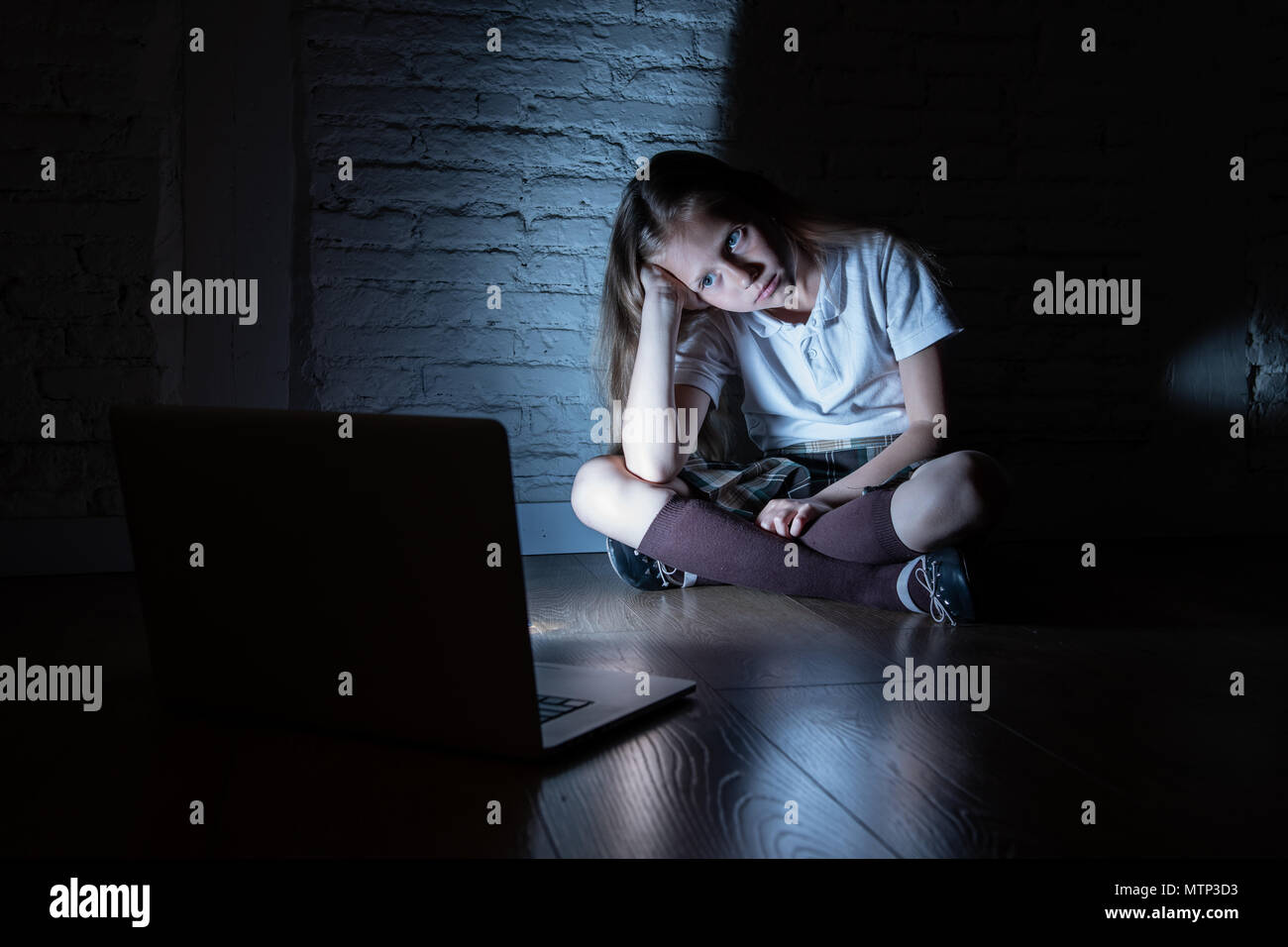 Scared sad girl bullied on line with laptop suffering cyberbullying and harassment feeling desperate and intimidated. Child victim of bullying stalker Stock Photo