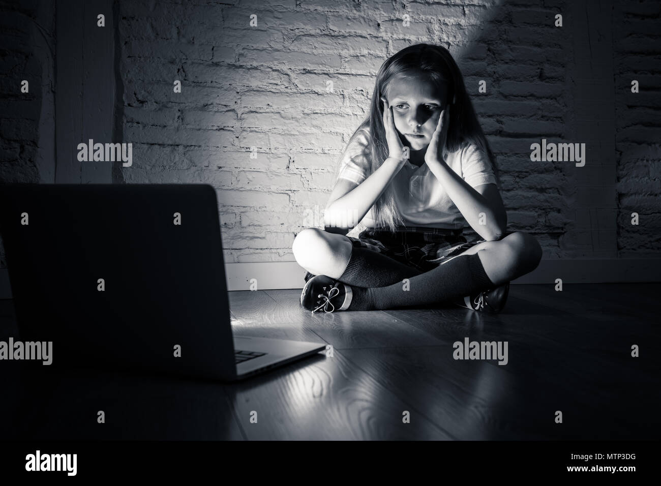 Scared sad girl bullied on line with laptop suffering cyberbullying and harassment feeling desperate and intimidated. Child victim of bullying stalker Stock Photo