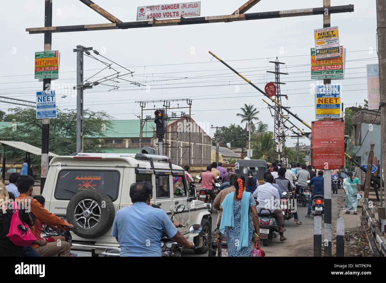 Pondicherry, India - March 17, 2018: Traffic and pedestrians streaming over a level crossing near the station after a passenger train has just passed Stock Photo